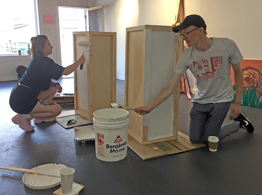Gallery assistants Brenna Noltner, at left, and Beck Slack paint pedestals for the upcoming exhibit.