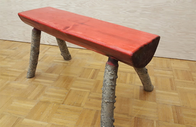 The finished benches are a variety of designs and sizes, such as this one with a stained seat and natural log legs.