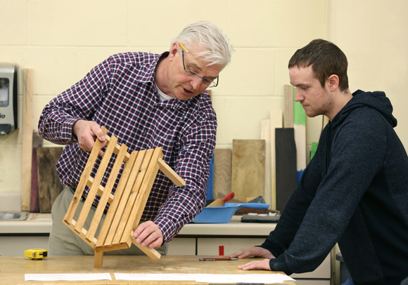 Professor Jerome Johnson, left, discusses a bench model with a student.