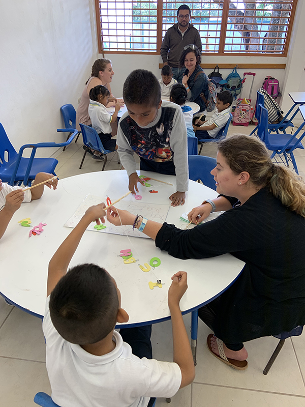 UW-Stout students Heidi Fliehs, front table, and back table Amayssia Wahljohnson, left, and Kristen Pease help children in a Cozumel, Mexico, school with activities.