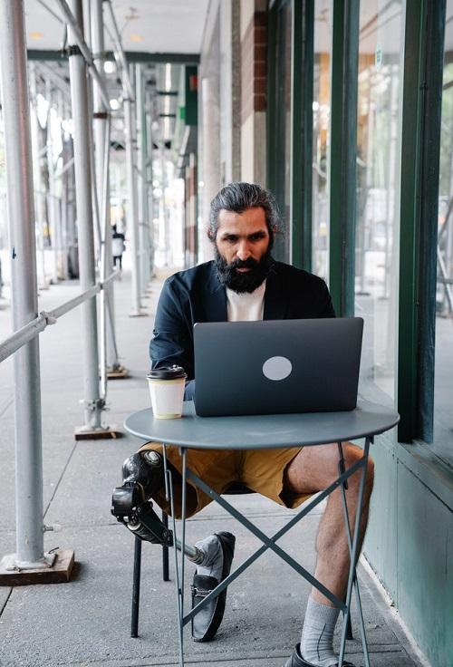 Man with prosthetic leg working on a laptop