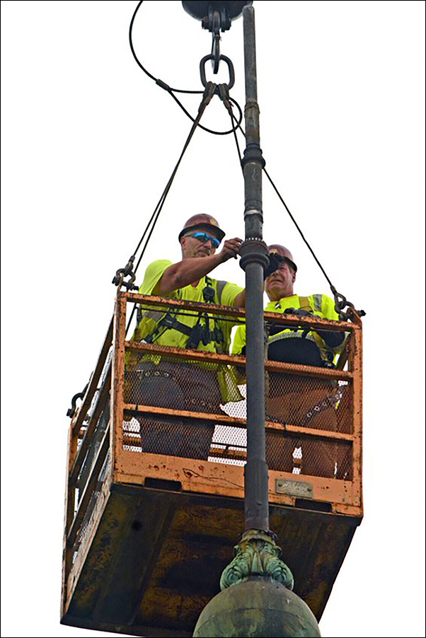 Two workers from Building Restoration Corp. hang from a basket during the effort to remove the quill and its support hardware. The project took 4½ hours.