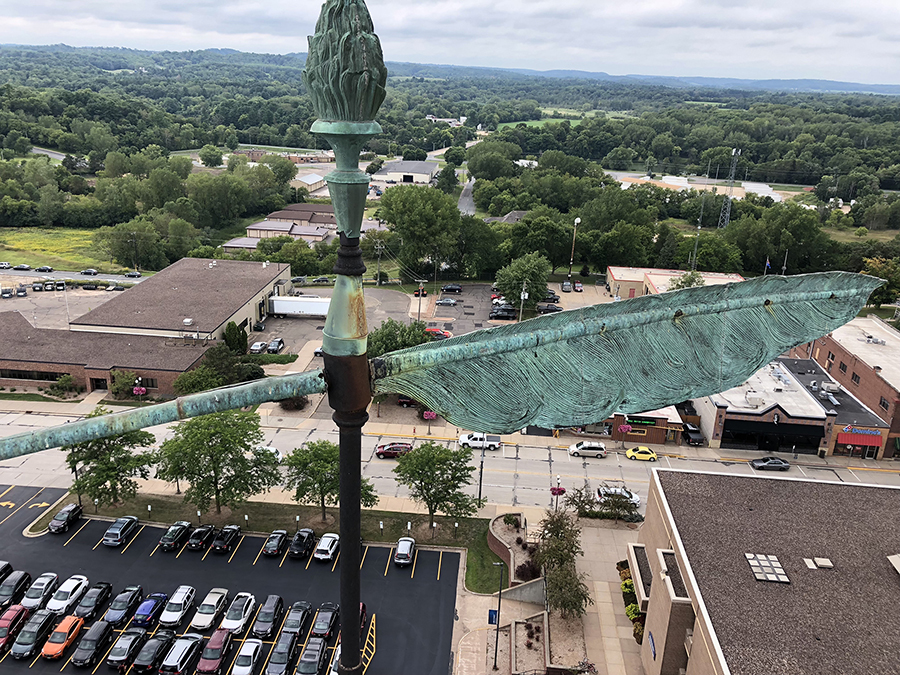 Workers photographed the quill weathervane and torch, looking west over Broadway Street, atop UW-Stout’s 135-foot Clock Tower just before removing it in late August.