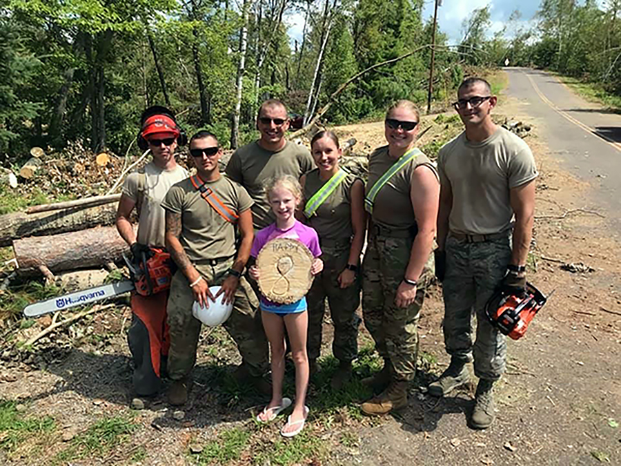 ​​​​​​​Alysha Stieber, third from right, and other Wisconsin National Guard members present a girl with a birthday memento made from a fallen tree while on duty this summer near Loon Lake in Barron County.