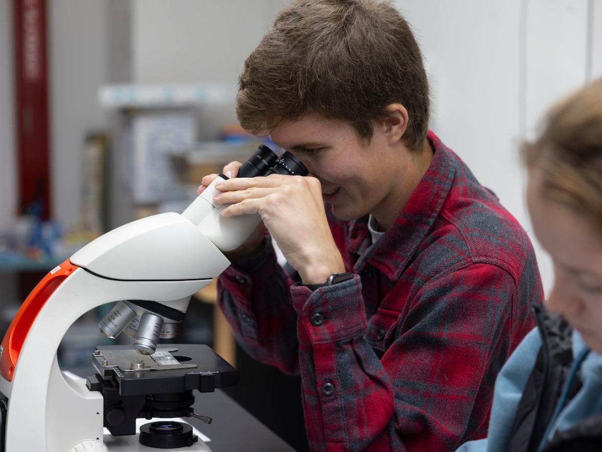 A student looking into a microscope